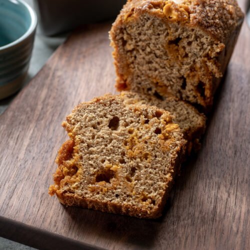 Apple butter quick bread sliced on a cutting board, with two slices stacked.