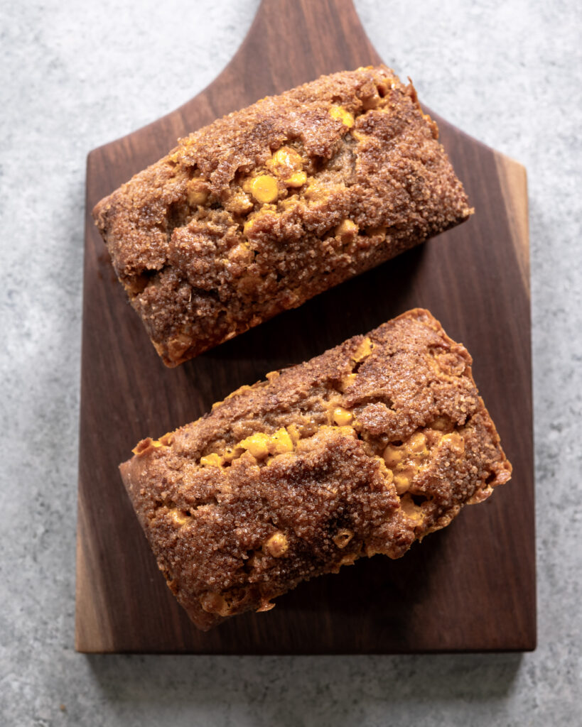 Two mini loaves of apple butter quick bread sitting on top of a wooden cutting board.