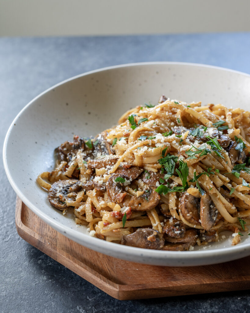 Creamy mushroom pasta in a white pasta bowl as seen from looking towards the food at 45 degrees.