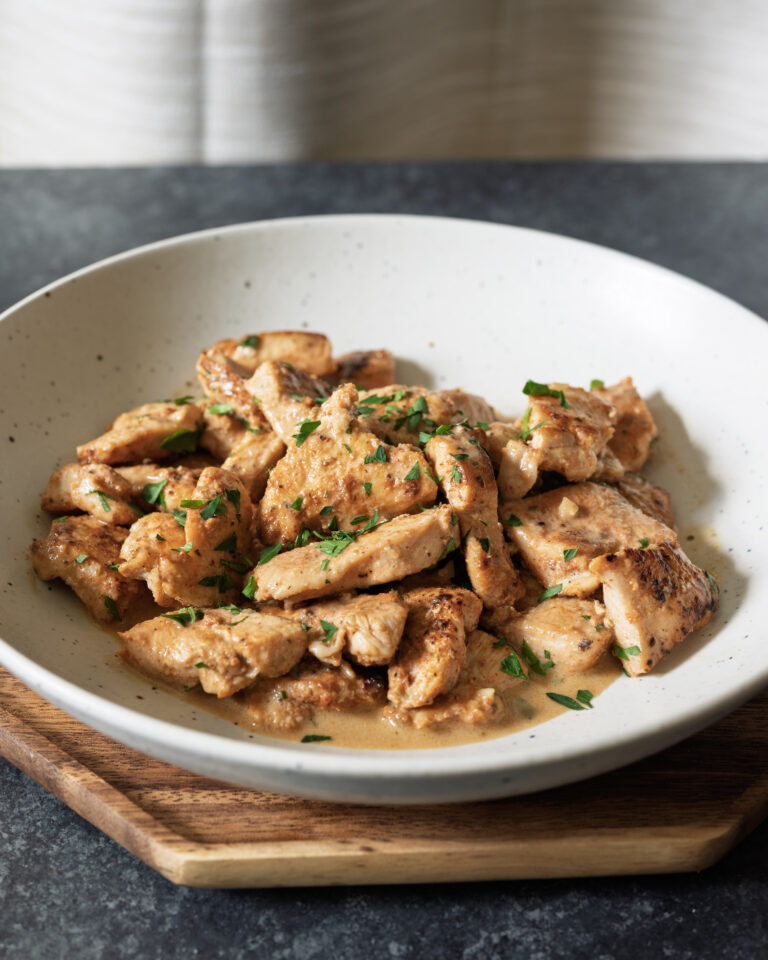 Creamy skillet chicken with golden-brown chicken breast pieces in a beer pan sauce, garnished with fresh parsley.